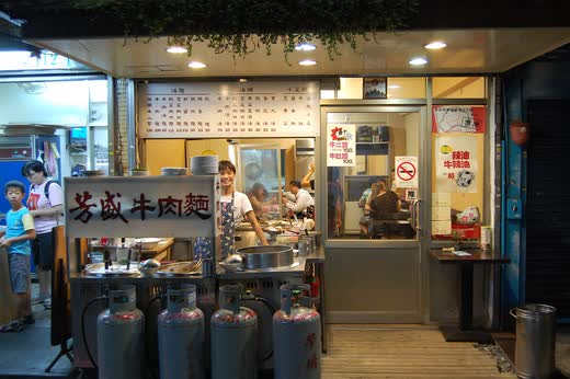Fachada abierta de un local de fideos de ternera, con el cartel en chino y la cocina a la vista