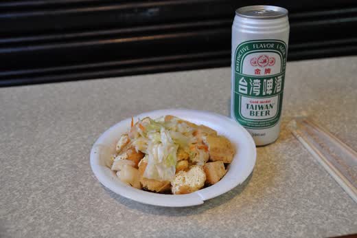 Plato de tofu apestoso frito con col encurtida y una cerveza Taiwan