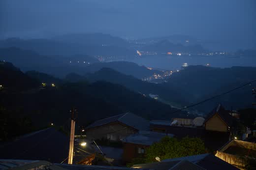 Vista nocturna desde Jiufen sobre las montañas hacia las luces de la costa