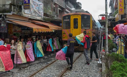 Tren amarillo pasando por la calle de Shifen entre puestos y gente con farolillos