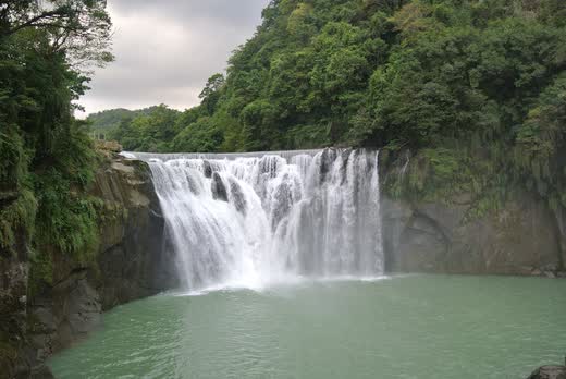 Cascada ancha de Shifen cayendo en una poza verde