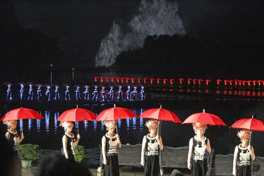 Figurantes con paraguas rojos en el espectáculo Impression Liu Sanjie