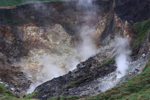 Ladera de rocas amarillas con fumarolas de vapor saliendo del suelo