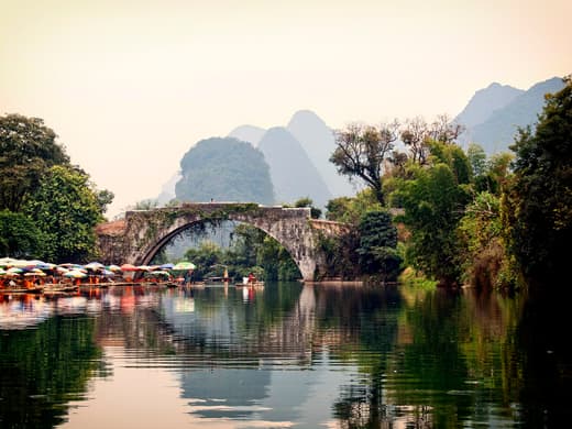 Puente de Yulong al atardecer con balsas amarradas