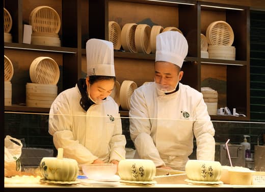 Cocineros preparando xiaolongbao a la vista del público