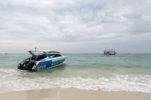 Lancha rápida varada en la arena junto a un barco de pesca