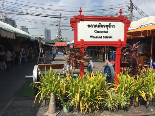 Puerta roja con el cartel del mercado de Chatuchak y puestos de plantas